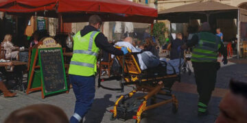 Malore in piazza a Victoria, anziano trasportato in barella tra tavoli e sedie fino all’ambulanza